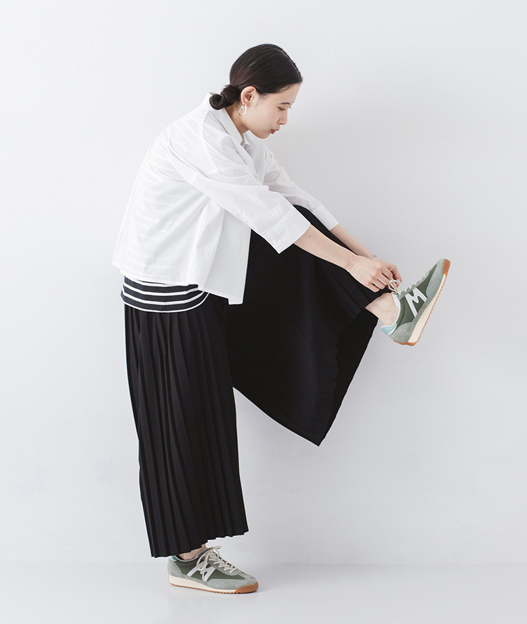 モデルがメスタリのティーのスニーカーを履いて靴ひもを結んでいる