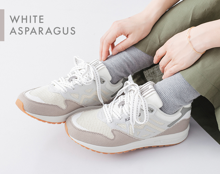 レガシー96のホワイトアスパラガスのスニーカーを履いた足元と手元のアップ