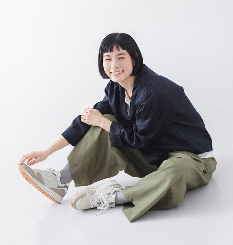 モデルがレガシー96のホワイトアスパラガスのスニーカーを履いて座っている