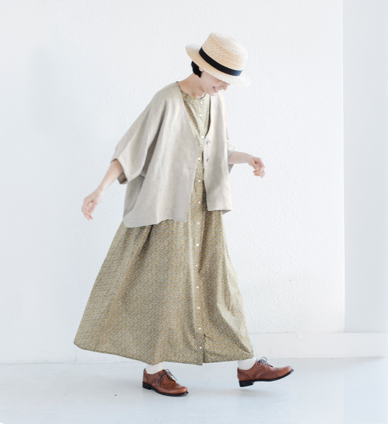 ナチュラルのリネンジャケットを花柄ワンピースに重ね、ストローハットを合わせて片足を上げた着用コーディネート画像