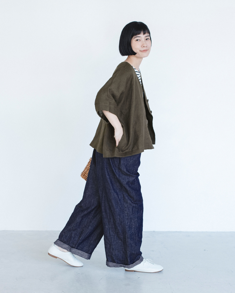 カーキのリネンジャケットをボーダートップスとダークデニムに合わせ、かごバッグを背面に持った着用コーディネート画像