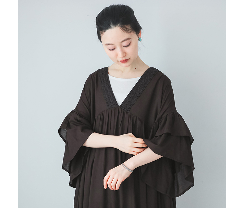 モデルがレーヨンフリルギャザーワンピースを着て袖のフリルを手で触れている