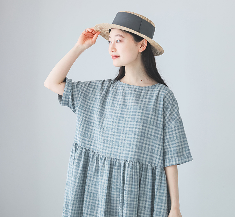 モデルが【ロング丈】サッカーウエストギャザーワンピースを着て帽子に手を添えている上半身