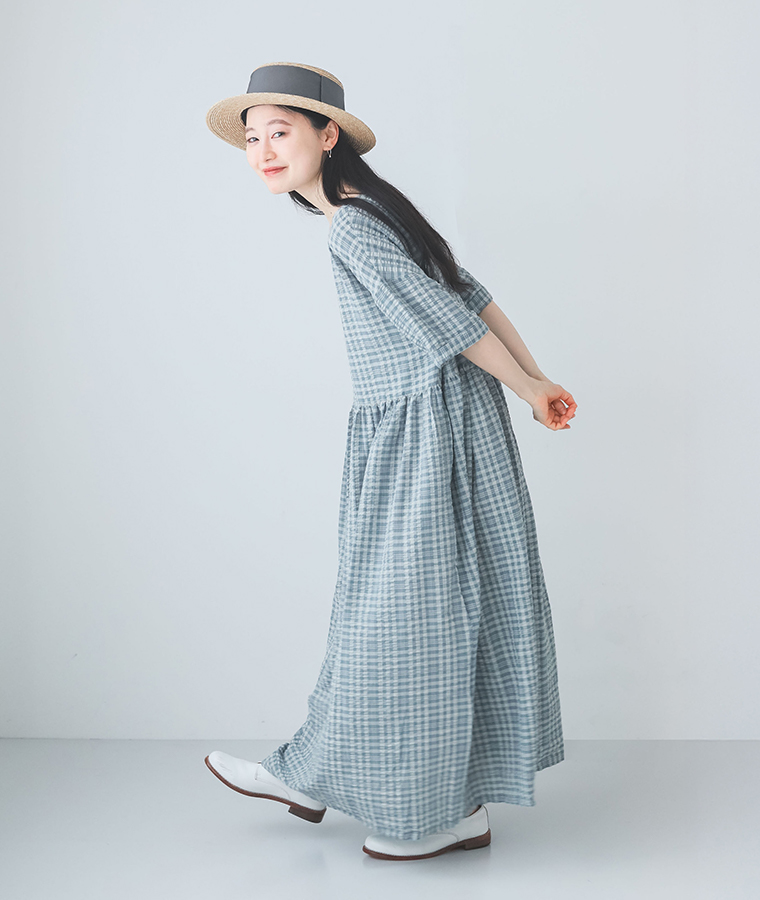 モデルが【ロング丈】サッカーウエストギャザーワンピースを着て横向きで歩いている