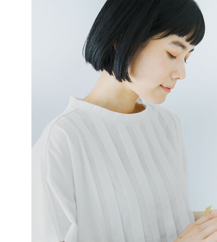 オフホワイトの半袖トップスを横向きで着用した人物のコーディネート画像