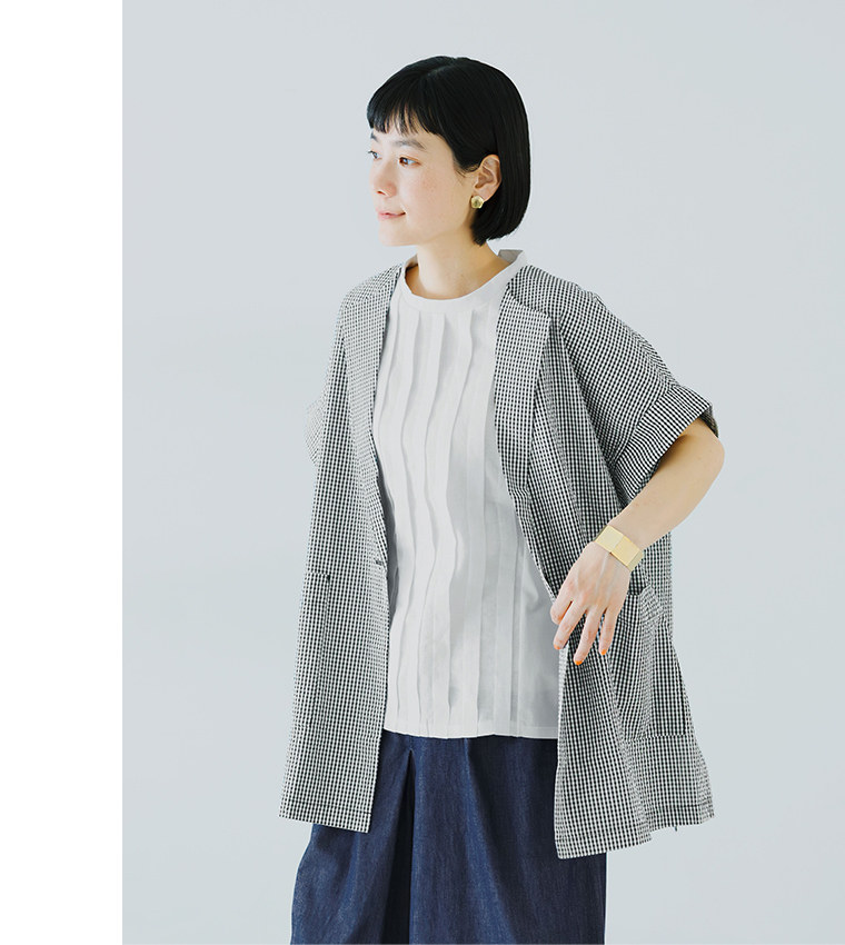 オフホワイトのトップスにチェック柄のショートスリーブ羽織りを重ねた着用コーディネート画像（ネイビーのワイドパンツ）