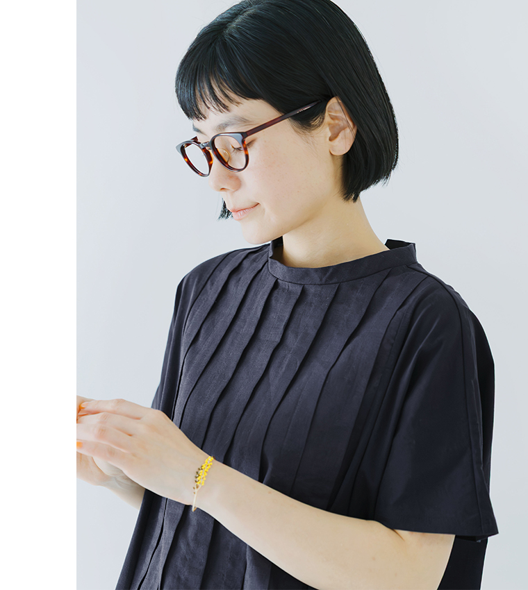 ネイビーの半袖トップスを着用した人物が手元を見つめるバストアップの着用コーディネート画像