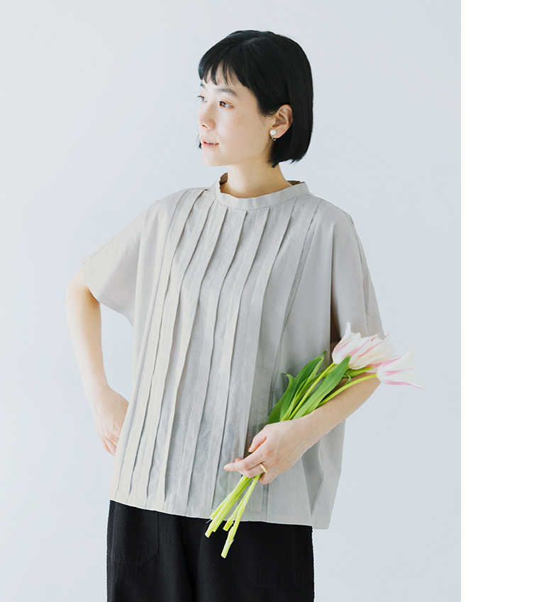 ライトグレーの半袖トップスにブラックのパンツを合わせた人物がチューリップの花束を手に持つ着用コーディネート画像