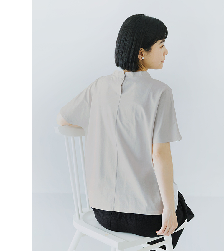 ライトグレーの半袖トップスを着用した人物が椅子に座る後ろ姿のコーディネート画像