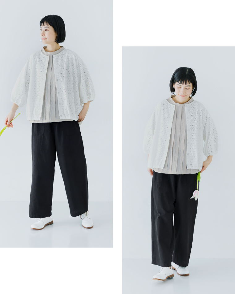 アイレット柄の七分袖羽織りにライトグレーのトップスとブラックのワイドパンツを合わせた人物が花を手に持つ着用コーディネート画像（2カット）