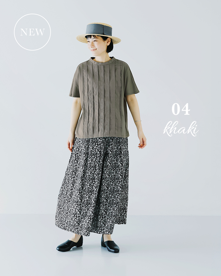 カーキの半袖トップスにブラックの花柄スカートと黒シューズを合わせた人物がハットをかぶる着用コーディネート画像