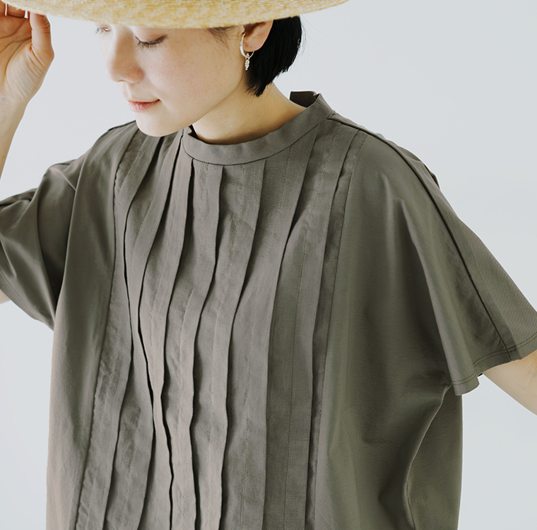 カーキの半袖トップスを着用した人物がハットをかぶるバストアップの着用コーディネート画像