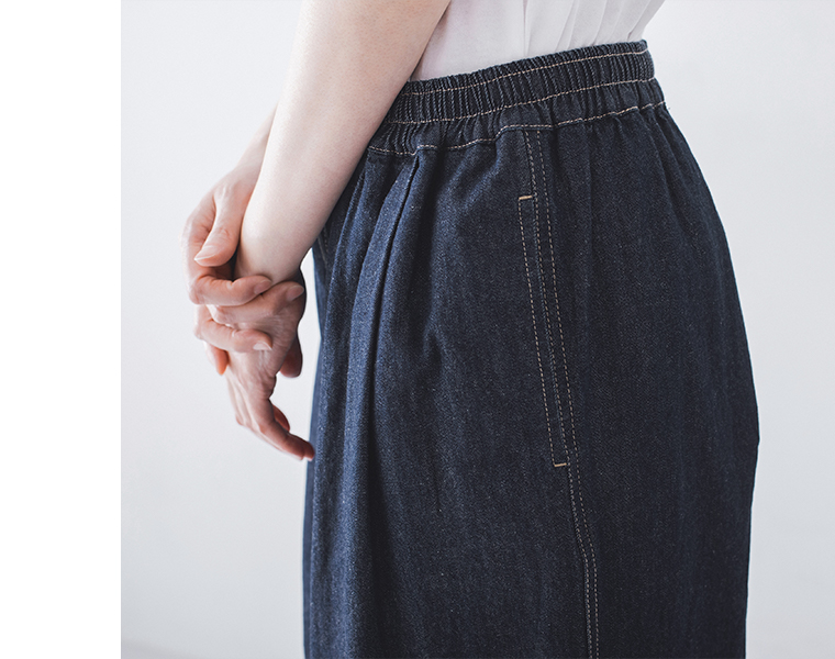 インディゴデニムのウエストゴム仕様とステッチを横から写した着用ディテール画像（白トップス合わせ）