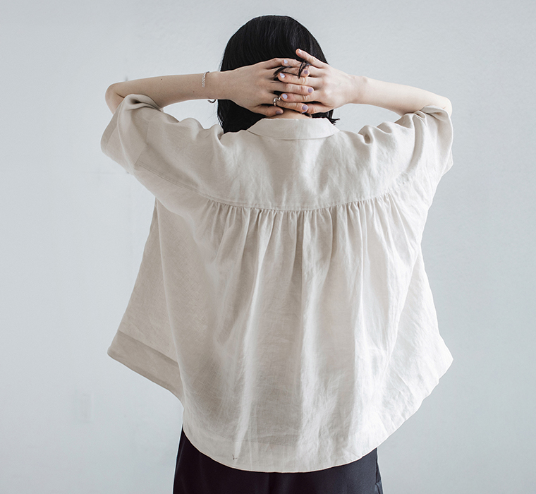 100%リネンちび襟シャツアイスグレーを着たモデルが背中側で手を組んでいる