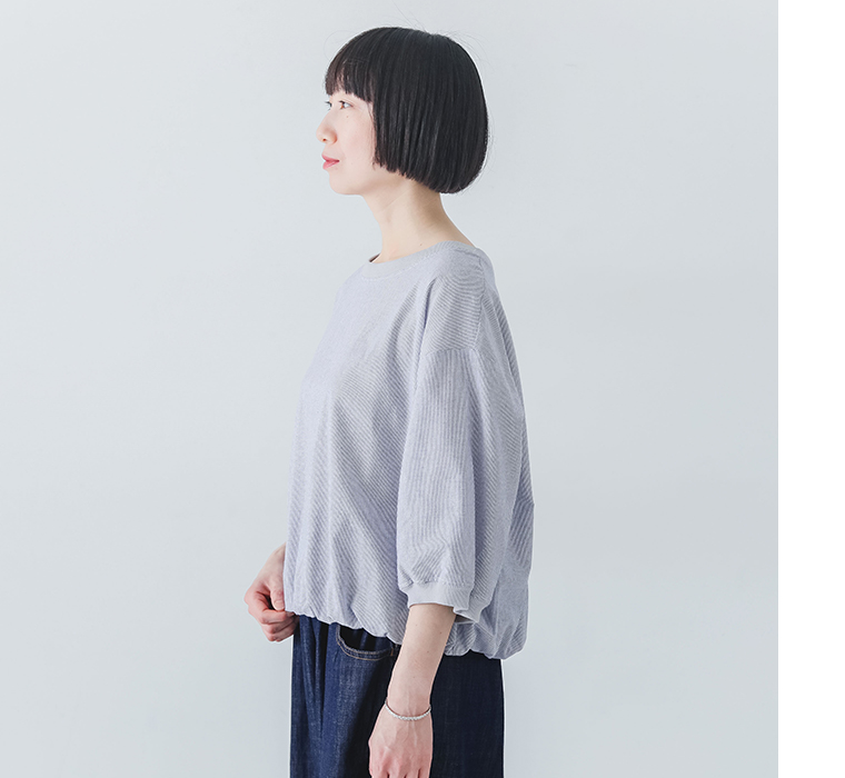 リネンタッチころんとかわいいハーフスリーブブラウスを着たモデルが横向きで立っている