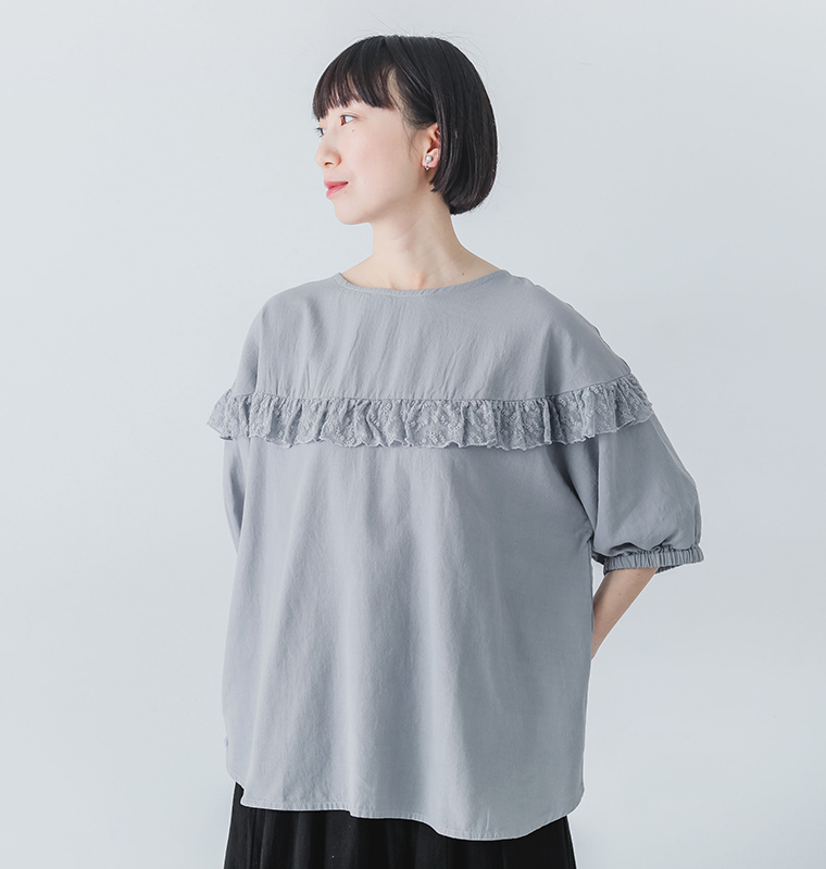 NUEVO BLANCAのラウンド切替レースフリルプルオーバーを着たモデルが左を向いている