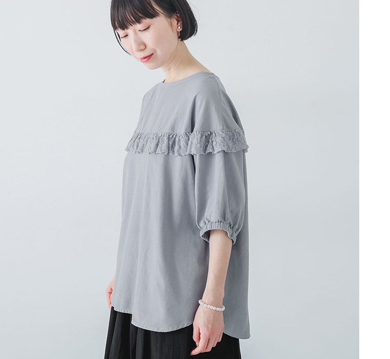 ラウンド切替レースフリルプルオーバーを着たモデルが横向きで立っている