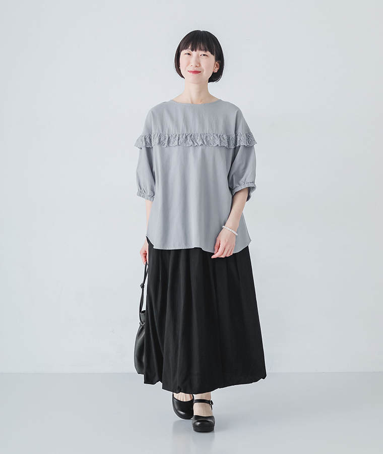 ラウンド切替レースフリルプルオーバーを着たモデルが正面で立っている