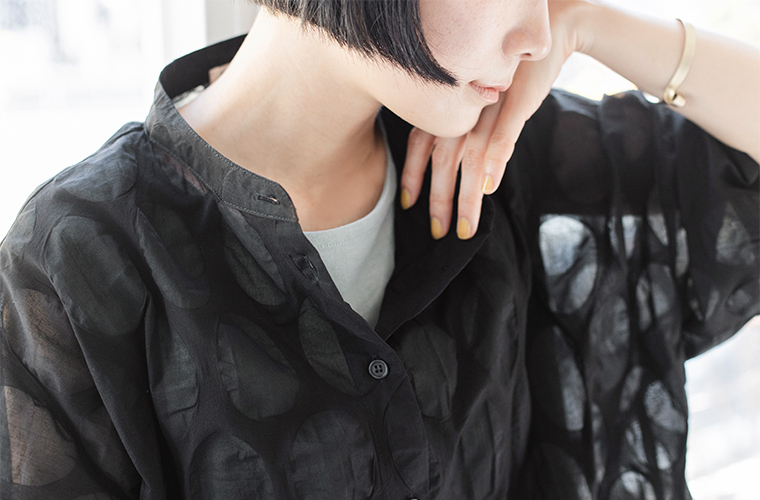 ブラックのシアーシャツを着た人物の上半身アップ（インナーとの透け感と楕円ドット柄の質感が見えるカット）