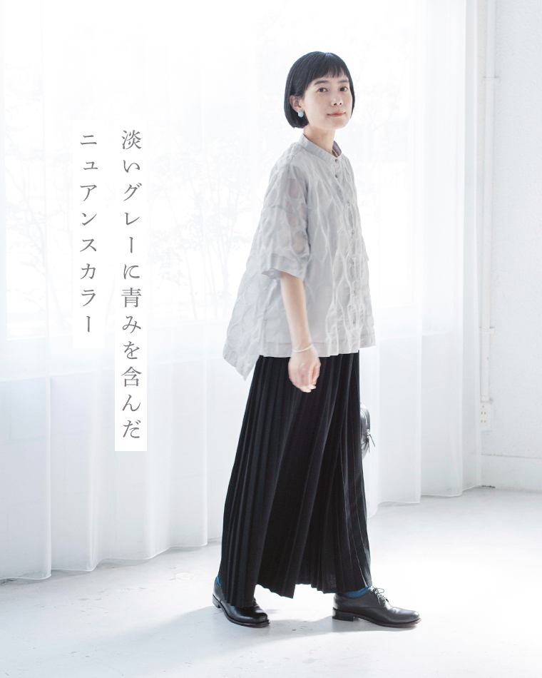 ライトグレーのトップスに黒のプリーツスカートを合わせた人物のコーディネート画像（青みを含んだニュアンスグレー）