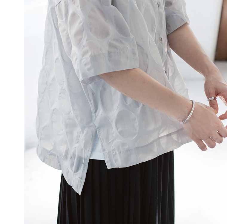 ライトグレーのシアートップスの袖と身頃まわりを写した質感ディテールカット（楕円ドット柄と透け感が見えるデザイン）