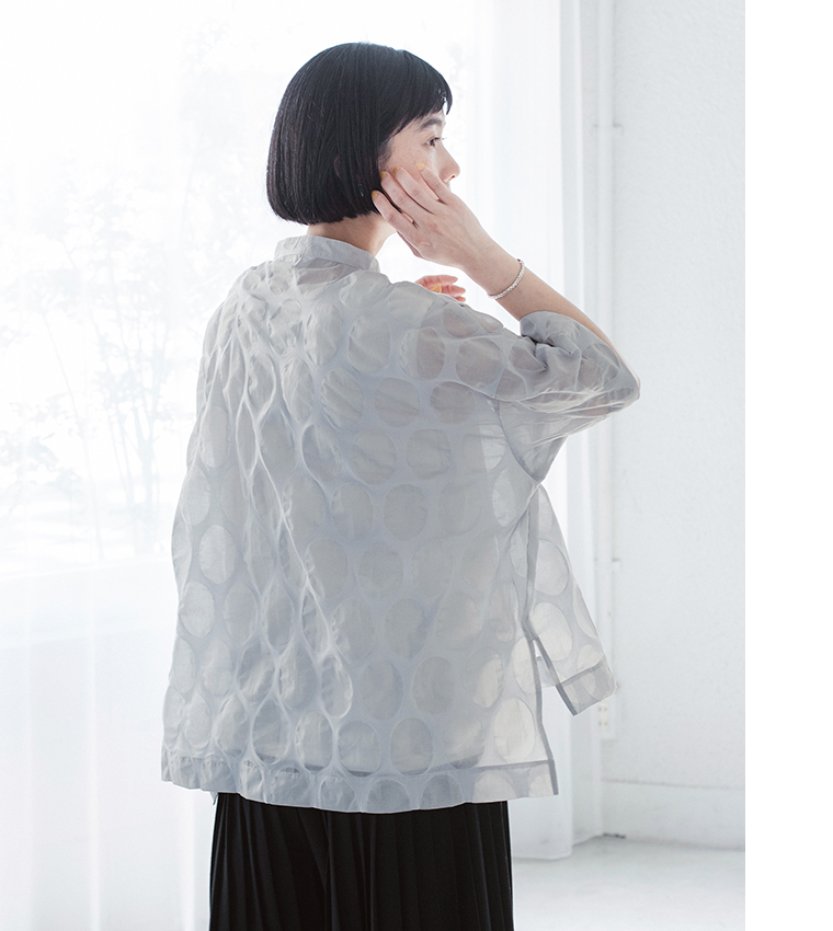 ライトグレーのシアートップスを着た人物の後ろ姿カット（楕円ドット柄の透け感がやわらかく見えるデザイン）