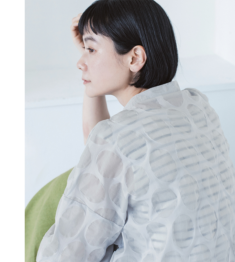 ライトグレーのシアートップスをボーダーの上に重ねた人物の上半身カット