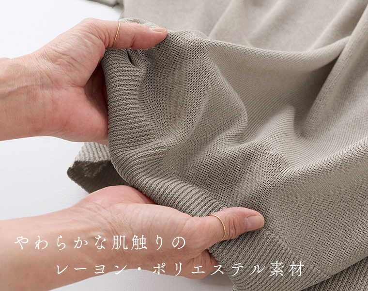 5分袖ニットカーディガンのベージュの生地を手でつまんでいる