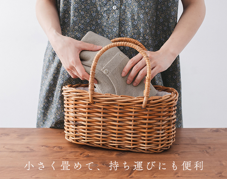 5分袖ニットカーディガンを畳んでかごに入れている手元