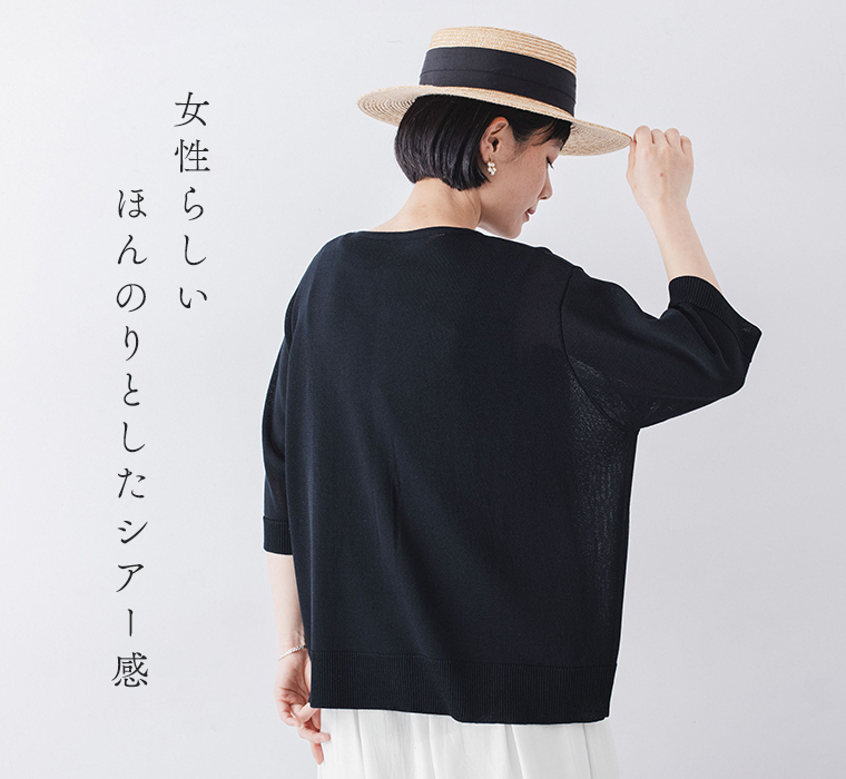 5分袖ニットカーディガン ネイビーを着たモデルが後ろを向いて帽子に手を添えている