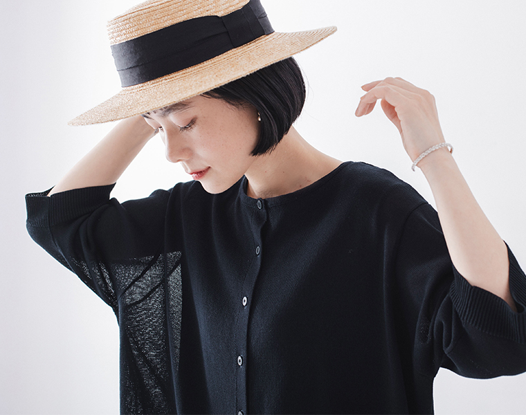 5分袖ニットカーディガン ネイビーを着たモデルが帽子に手を添えている