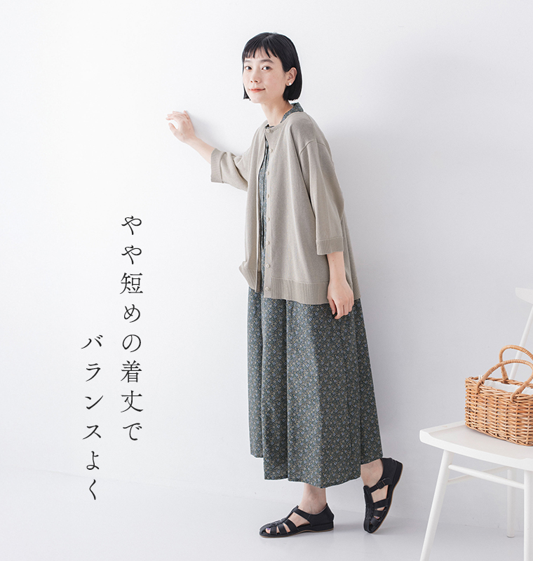 5分袖ニットカーディガン ベージュを着たモデルが横向きで壁に手を添えている