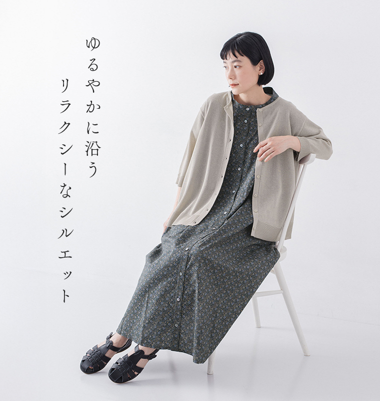 5分袖ニットカーディガン ベージュを着たモデルが椅子に座っている