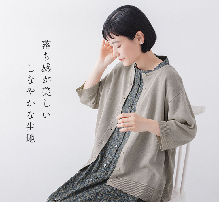 5分袖ニットカーディガン ベージュを着たモデルが座って横を向いている