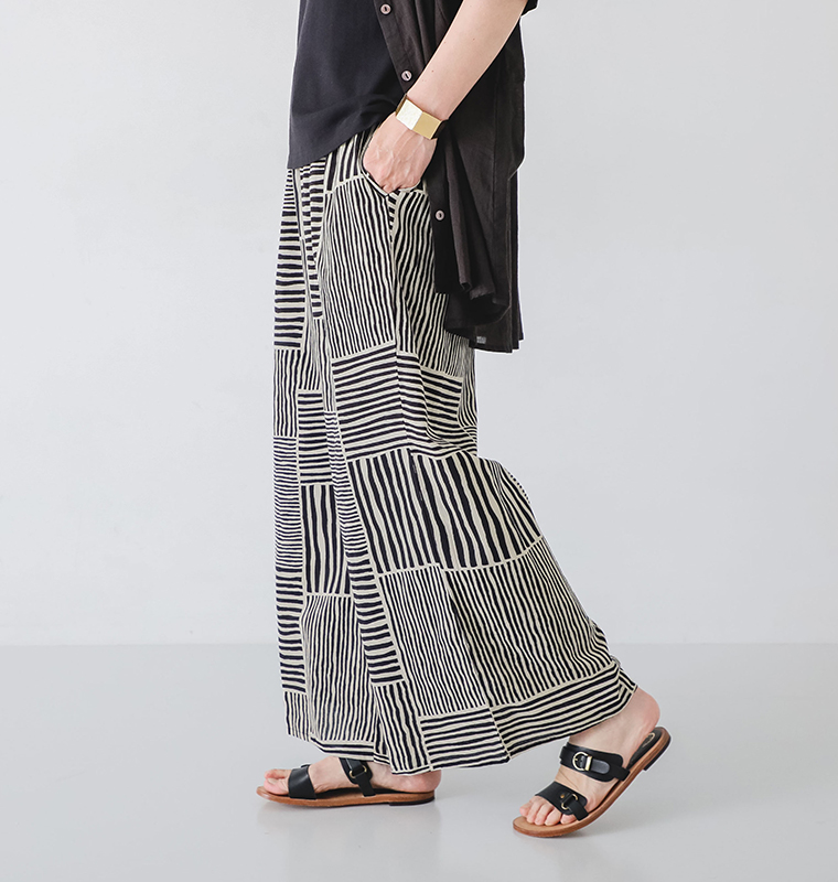 ストライプパンツを着たモデルが横向きで歩いている