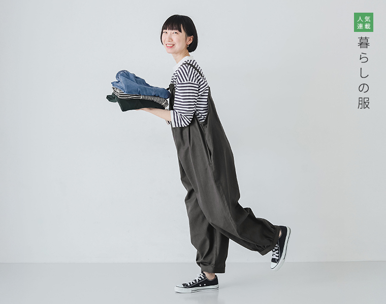 暮らしの服　ごきげんになれるサロペットを着たモデルがパンツを持って歩いている