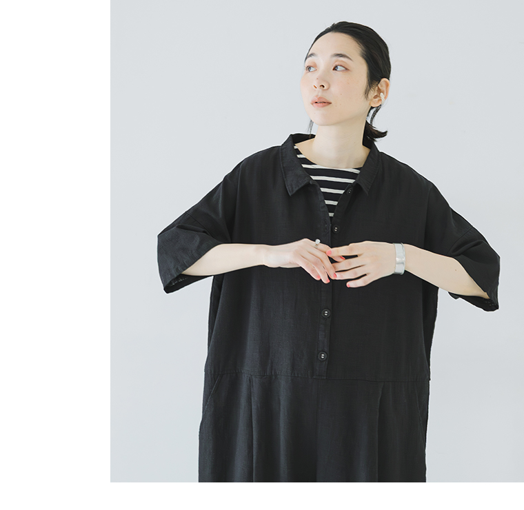 ブラックのオールインワンをストライプインナーに重ねた人物の上半身コーディネート写真