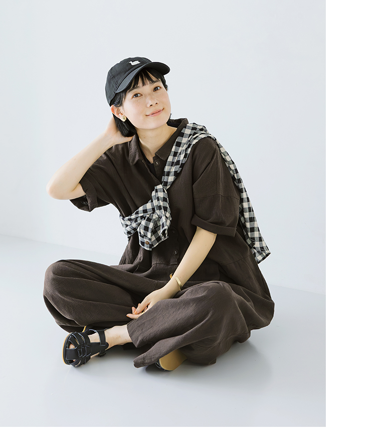 ラウンのオールインワンを着用した人物が床に座る全身コーディネート写真