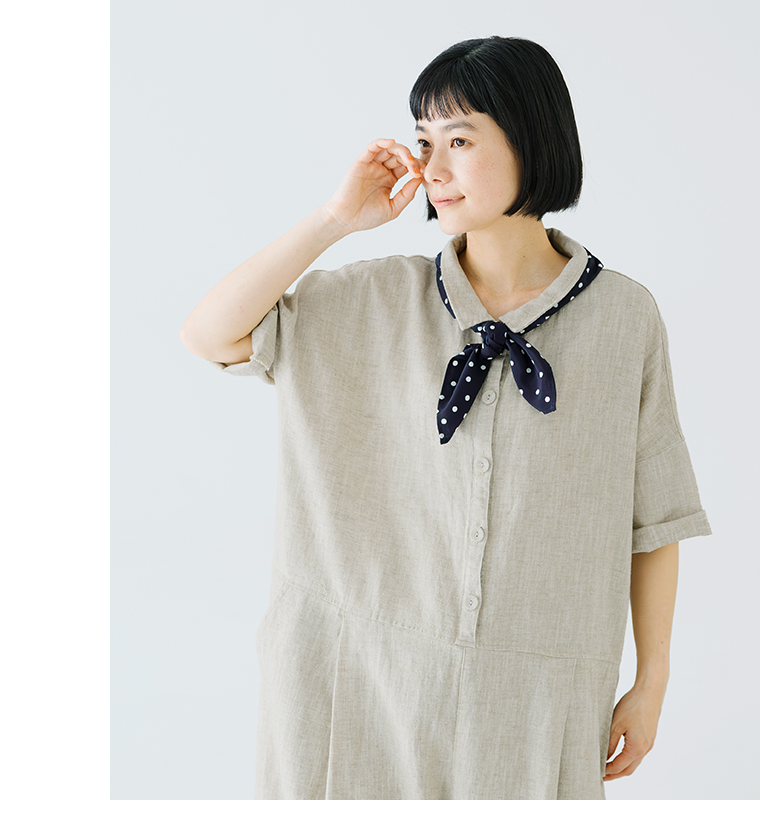 ナチュラルカラーのオールインワンにドット柄スカーフを合わせた人物の上半身コーディネート写真