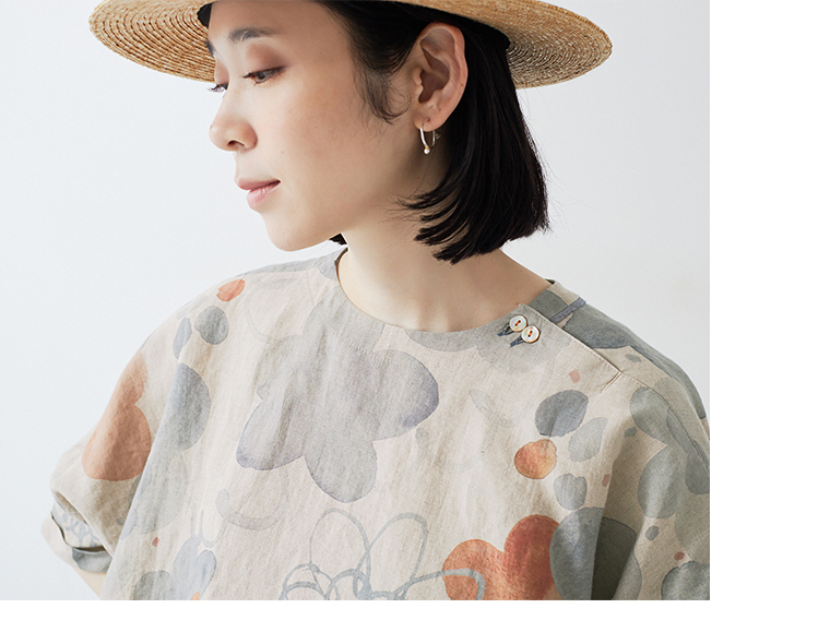 水彩タッチの花柄リネンシャツを着た人物の横向きカット（肩のボタンディテールが見える）