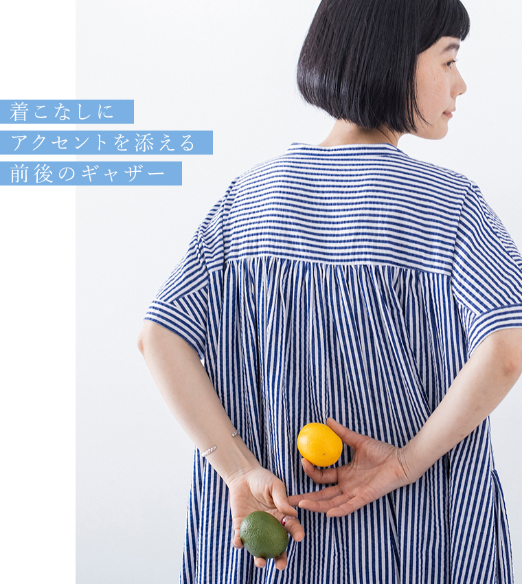 「着こなしにアクセントを添える 前後のギャザー」の文字が添えられた、ストライプワンピースのバックディテール（レモンとライムを手にしたカット）