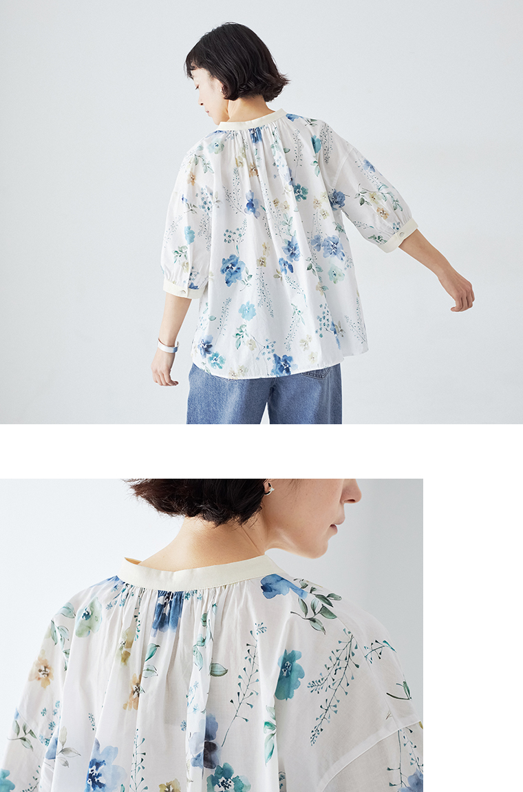 ブルーの花柄ブラウスのギャザーとドロップショルダーを見せた着用画像
