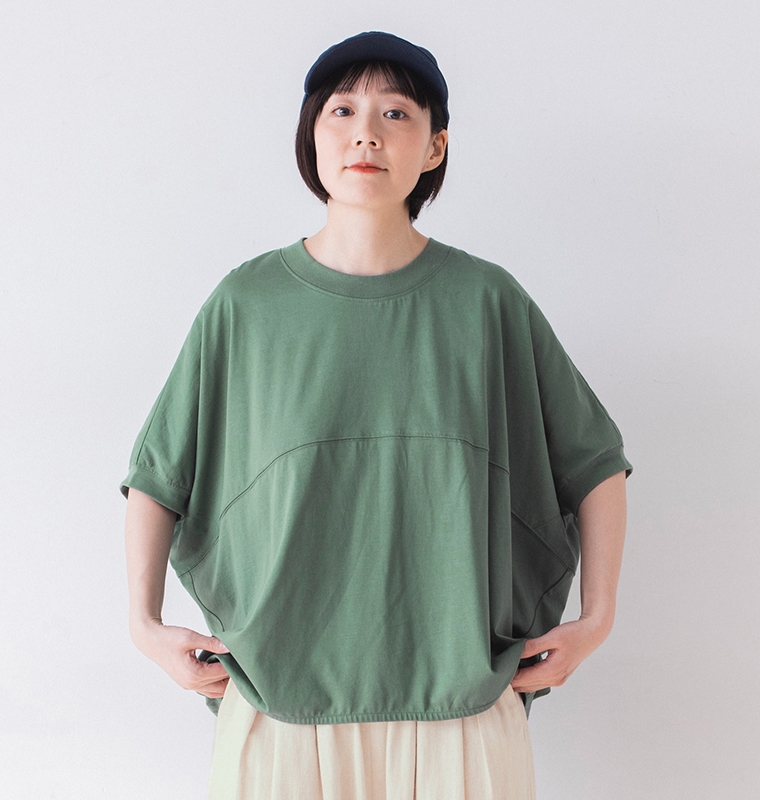 &yarn ポンチョプルオーバー（グリーン）を着用した人物の正面アップ — ゆったりとしたシルエットと胸元の切り替えラインが特徴