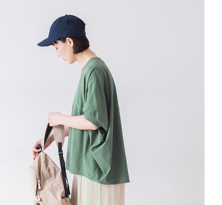 &yarn ポンチョプルオーバー（グリーン）を着用した人物の横向きコーディネート — ベージュのリュックを持ったナチュラルなスタイリング