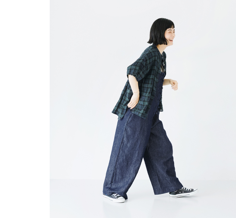 Dgy コットンリネンデニムチャイナボタンサロペットの横向きコーディネート（チェックシャツを羽織り、軽やかに歩く姿。ゆったりとしたシルエットが際立つカジュアルスタイル）