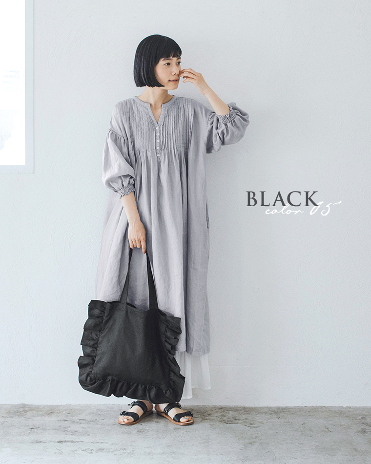 08Mabの リネンフリルトートバッグ（ブラック）を手にした女性のコーディネート画像。ライトグレーのピンタックワンピースに黒のサンダルを合わせ、シックで落ち着いた印象のスタイル。画像内テキスト「BLACK color 05」。