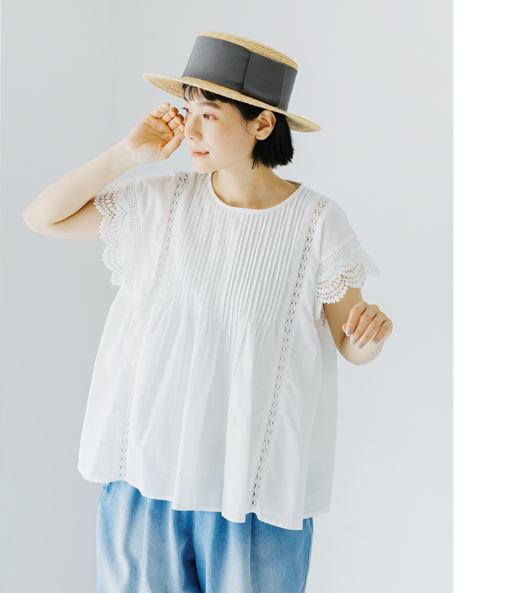 Lintu Lauluレースピンタックブラウス（ホワイト）の着用コーディネート画像。繊細なピンタックとスカラップレース袖が特徴で、軽やかなコットン素材がふんわりと広がるシルエット。麦わら帽子とデニムを合わせた爽やかなスタイリング。