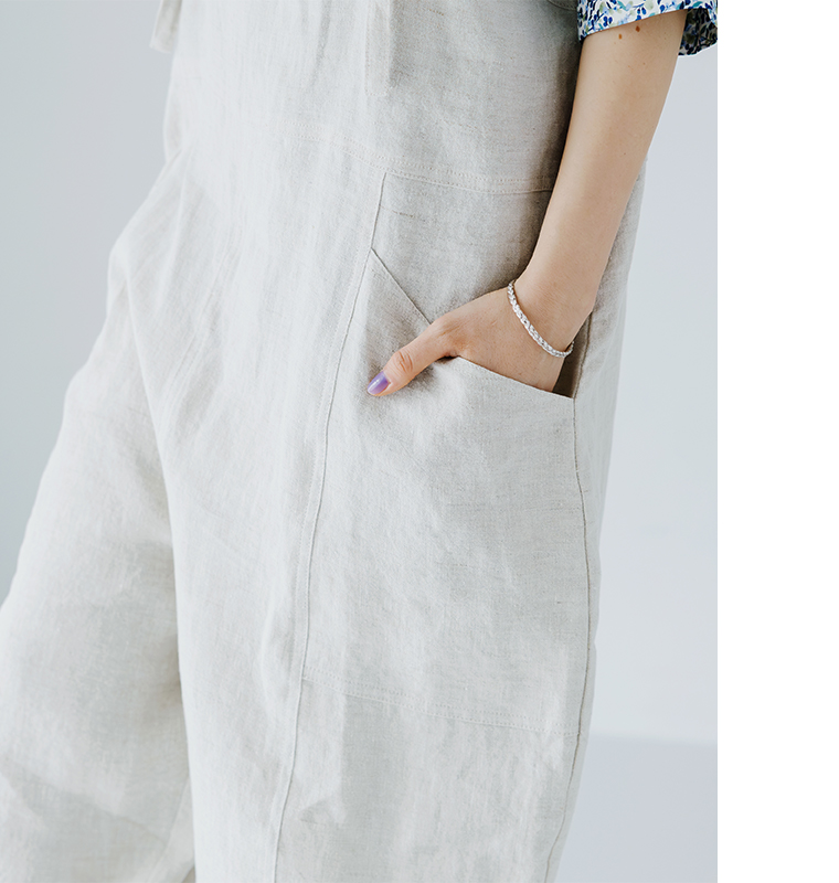 &yarn100％リネンバレルサロペット（ナチュラル）のポケットディテール画像。花柄シャツに合わせた着用カットで、リネン素材の風合いと大きめポケットのデザインを表現。