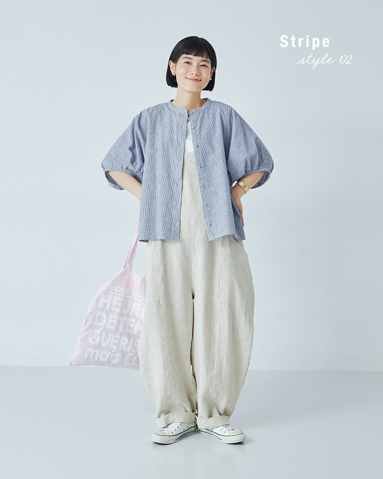 Bliss bunchのちょうちんスリーブブラウス（ブルーストライプ）を着用したモデルの全身コーディネート画像。白のサロペットに重ね、白のスニーカーとピンクのロゴ入りトートバッグを合わせた軽やかなスタイリング。背景に「Stripe style 02」の文字入りで、爽やかな印象を演出。