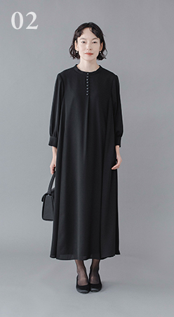 Luuna miu【慶弔両用】大切な日のボタンフレアワンピース着用イメージ。黒のロングワンピースを着たモデルがグレー背景の前に立ち、前ボタンのディテールと七分袖のシルエットが見える商品画像。フォーマルシーンにふさわしい上品な印象。